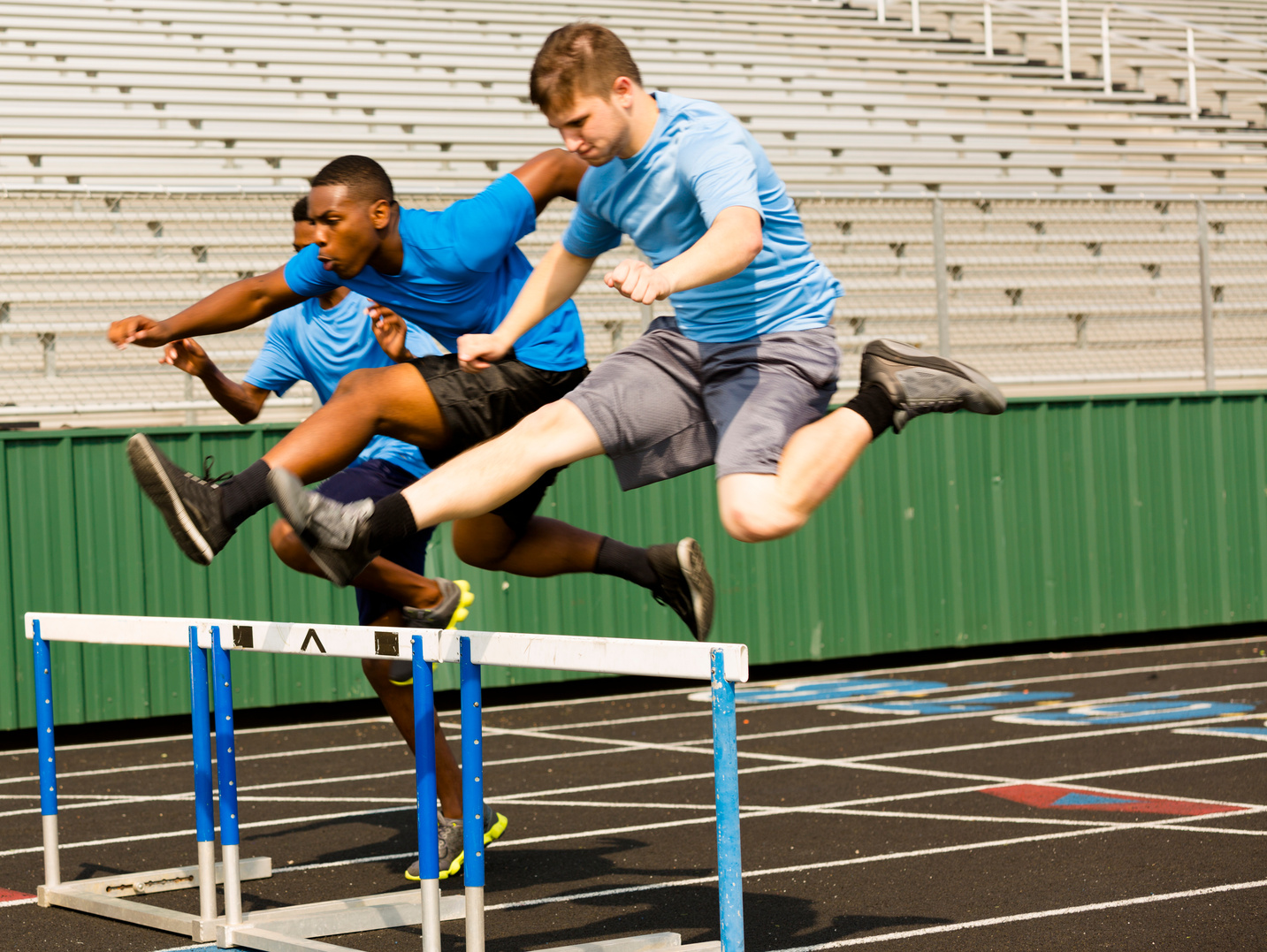 Sports: Three high school boys run a hurdles race.